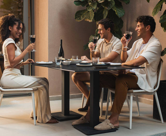 Three guests raising their wine glasses at an outdoor dinner table