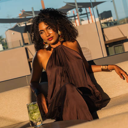 Une cliente se détend sur un canapé du rooftop lounge, un cocktail à ses côtés