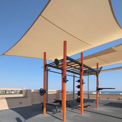 Salle de sport en plein air sur le toit, rack et banc sous voiles d'ombrage face à la mer
