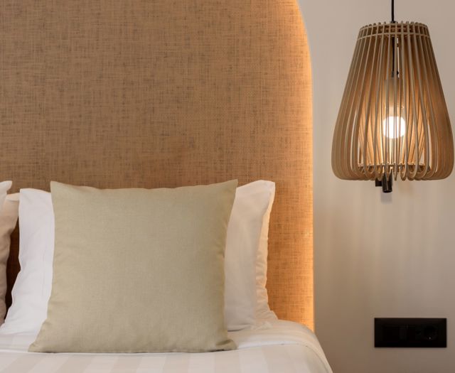 Gros plan sur les oreillers du lit avec tête de lit en tissu et suspension en bois
