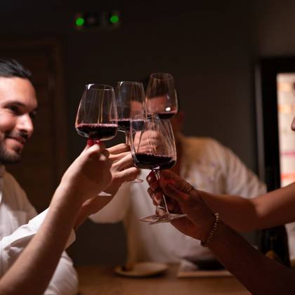 Gros plan de clients trinquant avec du vin rouge lors d'une dégustation