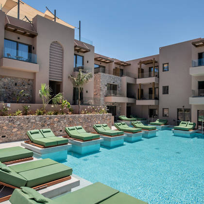 Piscine principale bordée de transats verts et entourée de balcons de suites