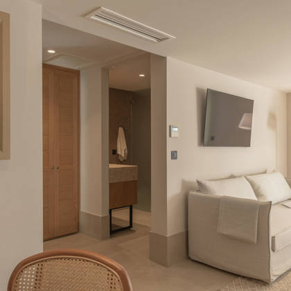 Coin salon de la Suite Junior Swim Up avec canapé, lampadaire et salle de bain avec vasque