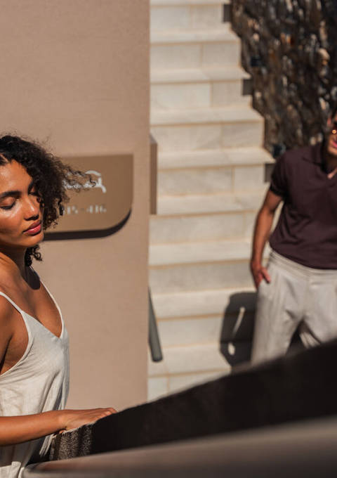 Couple on the outdoor stairs of the hotel beside the stone wall in the sunlight