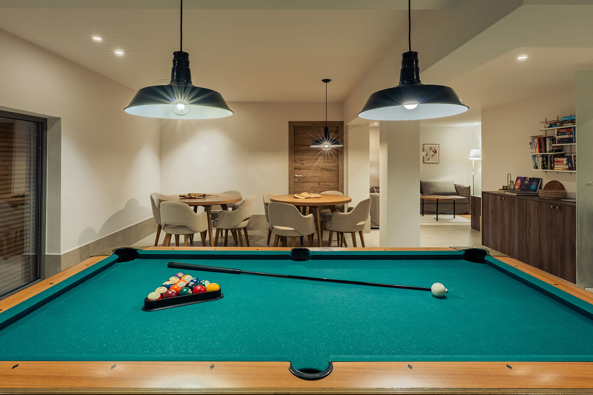 Billard prêt pour une partie dans le playroom, avec le coin lounge à l'arrière