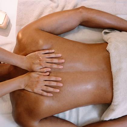 Gros plan de mains massant le dos d'un client avec de l'huile