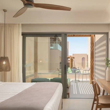 Chambre Deluxe avec lit double et bureau, ouvrant sur un balcon privé donnant sur le jardin