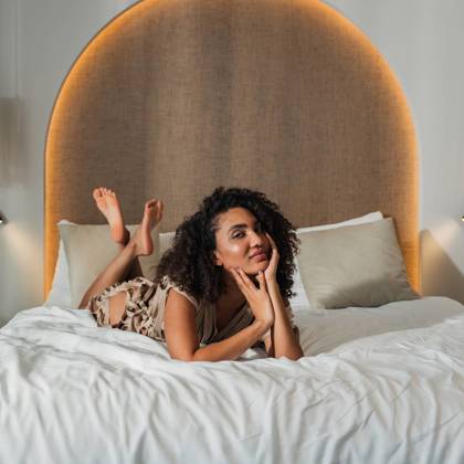 Guest relaxing on a king-size bed in a modern suite at Paralos Venus Suites in Crete.
