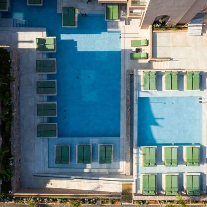 Vue aérienne de deux piscines côte à côte, bordées de rangées de transats verts