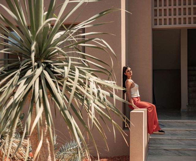Femme profitant du soleil près d'un palmier, à côté de l'escalier extérieur de l'hôtel