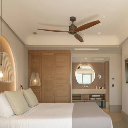 Suite Junior avec lit double, armoire en bois, télévision et salle de bain ouverte avec miroir rond