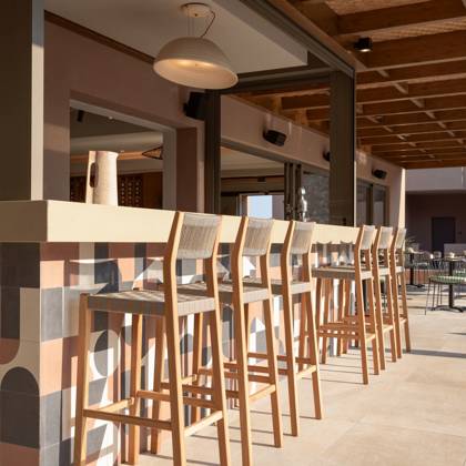 Rangée de tabourets en bois le long d'un comptoir carrelé sous un plafond en bois