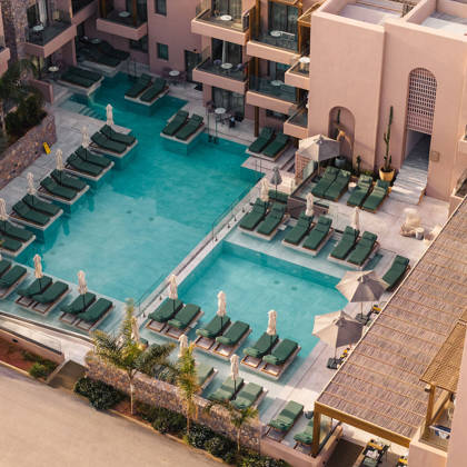 Les piscines principales entourées de transats, avec les balcons des suites derrière