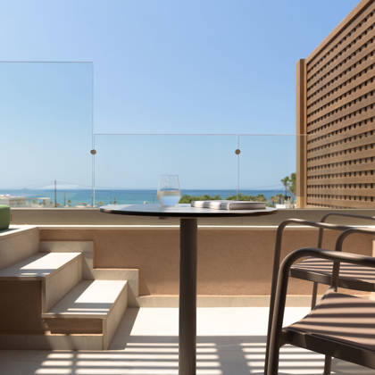 Terrasse de la suite avec table, chaises et marches vers la piscine privée, face à la mer