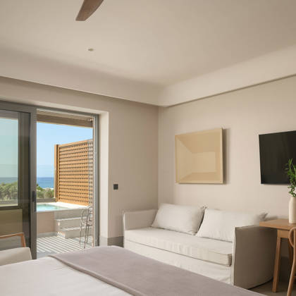 Suite Junior avec canapé, bureau et télévision, ouvrant sur une terrasse avec piscine privée et vue mer