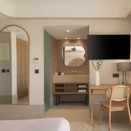 Détail de chambre Deluxe avec miroir arqué, bureau en bois et salle de bain ouverte avec vasque
