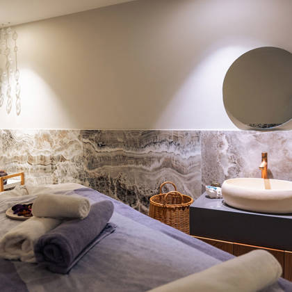 Salle de massage avec table de soin préparée, serviettes pliées et touches de marbre
