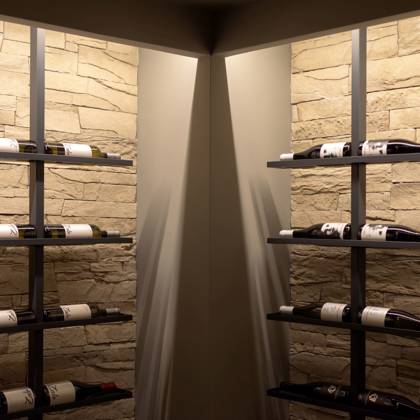 Bouteilles de vin sur casiers métalliques contre des murs en pierre, lumière douce
