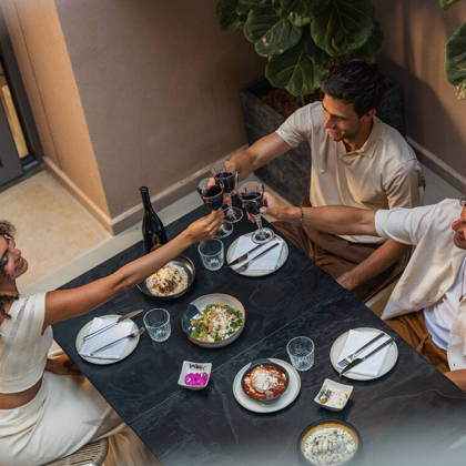 Trois clients trinquent au vin rouge pendant un dîner à la carte au restaurant