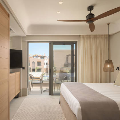 Suite Junior avec lit double, armoire en bois et télévision, ouvrant sur un balcon privé