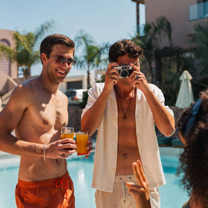 Un client photographie ses amis avec leurs cocktails au bord de la piscine