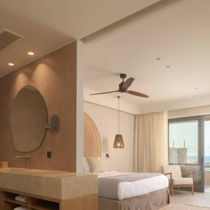 Suite Junior avec vasque ouverte, miroir rond et lit double face à la terrasse avec vue mer