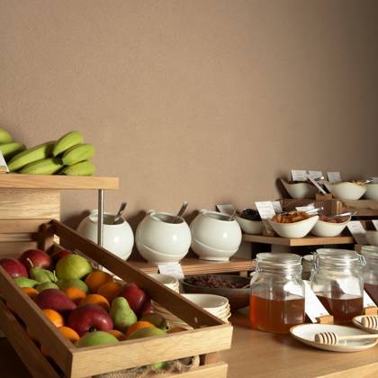 Buffet du petit-déjeuner avec fruits frais en cagettes, pots de miel, fruits secs et noix