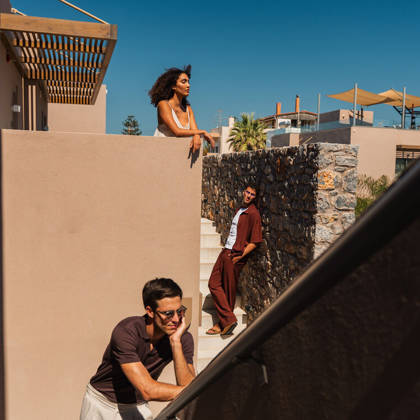 Des clients discutent dans l'escalier extérieur de l'hôtel sous un ciel bleu