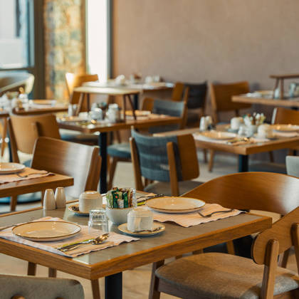 Tables en bois dressées pour le petit-déjeuner dans le restaurant principal