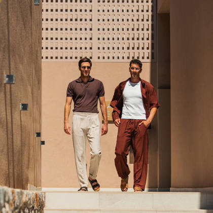 Deux clients descendent les marches de l'entrée de l'hôtel dans la lumière du soir