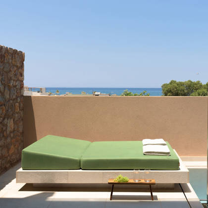Lit de repos avec serviettes près de la piscine privée de la suite, la mer en arrière-plan
