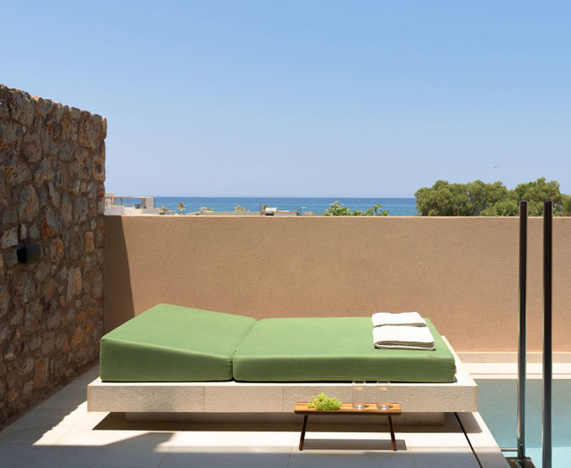 Lit de repos avec serviettes près de la piscine privée de la suite, la mer en arrière-plan