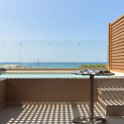 Piscine privée sur la terrasse d'une Suite Junior avec table, transat et vue dégagée sur la mer
