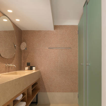 Salle de bain de Suite Junior avec vasque en pierre, miroir ovale et cabine de douche vitrée