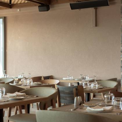 Salle à manger avec tables dressées, chaises en bois et murs en pierre aux tons terreux