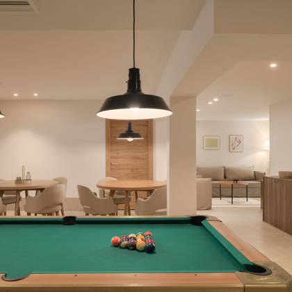 Salle de jeux avec billard, tables de jeux et canapé lounge au fond