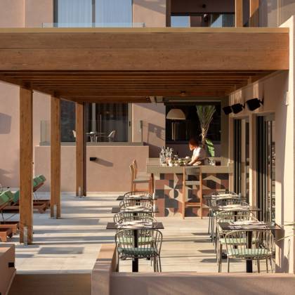 Terrasse ombragée avec pergola en bois, comptoir de bar et tables au bord de la piscine