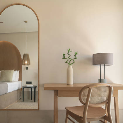 Détail de Suite Junior avec bureau en bois, chaise et grand miroir arqué reflétant le lit