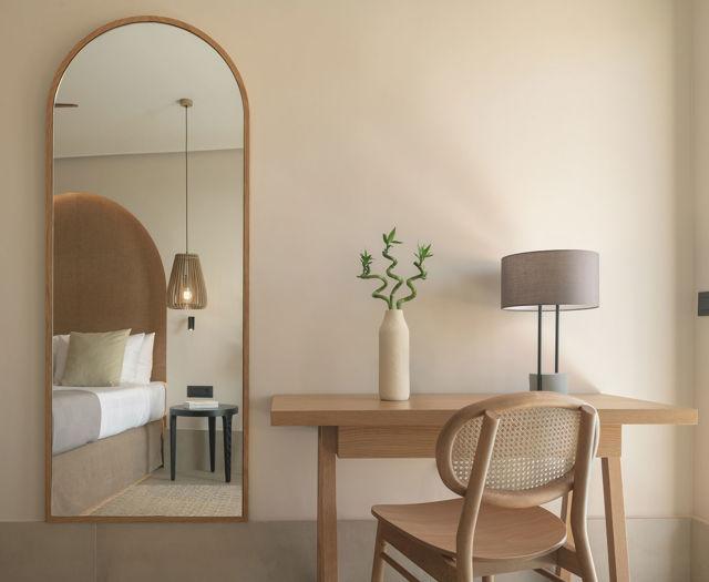 Détail de Suite Junior avec bureau en bois, chaise et grand miroir arqué reflétant le lit
