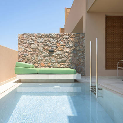 Piscine privée d'une Suite Junior avec lit de repos près d'un mur en pierre et coin salon ombragé