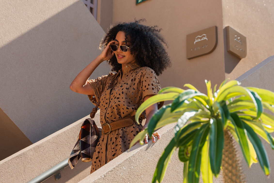 Guest in a summer dress and sunglasses walking down the stairs on a sunny day