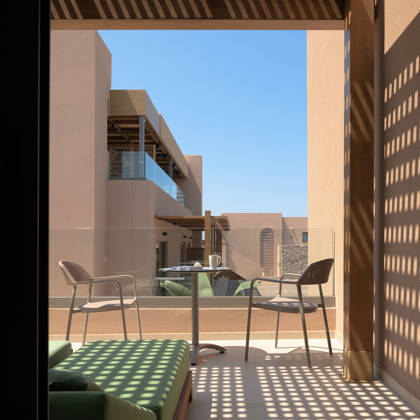 Balcon privé d'une chambre Deluxe avec coin salon et table, donnant sur les bâtiments de l'hôtel
