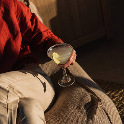 Client en chemise en lin rouge tenant une margarita au bord givré de sel avec une tranche de citron vert