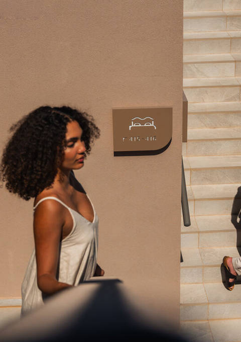 Couple on the sunlit stairs beside the stone wall and the hotel signage