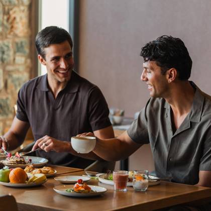 Two guests enjoying a Cretan breakfast with fresh fruit, pastries and coffee at Paralos Venus Suites.