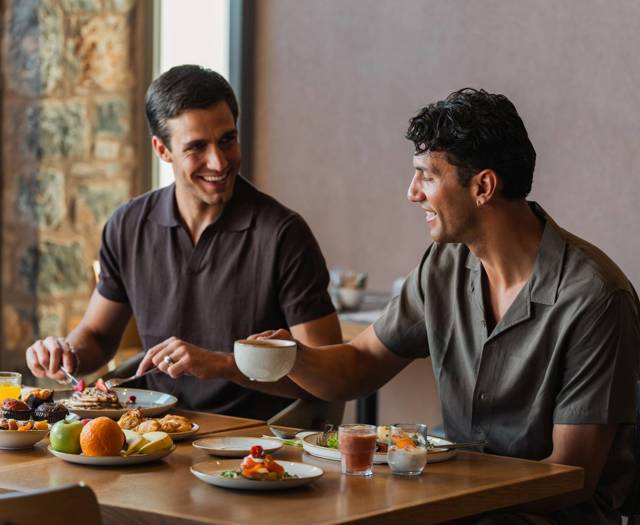 Two guests enjoying a Cretan breakfast with fresh fruit, pastries and coffee at Paralos Venus Suites.